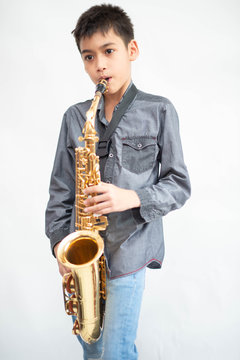 Little asian musician boy playing saxophone instrument