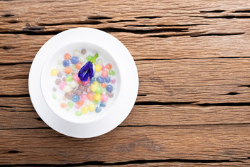 Thai sweets and colorful ball flour in a white cup on old wooden table Rainbow sweets, popular and famous Thai desserts, Bua Loi, Bua Loy, Pandan leaves