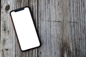 Mobile smart phone iphonE mockup with blank creen on wooden background.