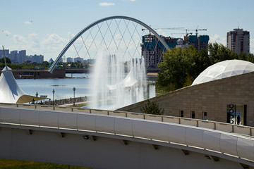 Fototapeta na wymiar Photo of a beautiful, modern pedestrian bridge on the background of the fountain and .