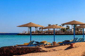 Sun umbrellas and chaise lounges on tropical beach. Concept of rest, relaxation, holidays, resort