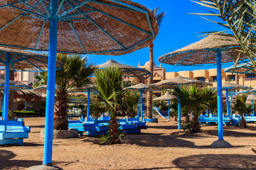 Sun umbrellas and chaise lounges on tropical beach. Concept of rest, relaxation, holidays, resort