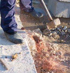 man smashes concrete with heavy sledgehammer