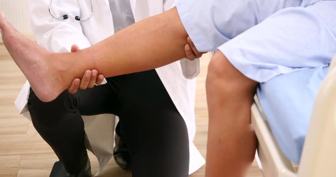 Doctor examining leg of patient in clinic