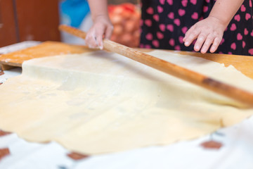 Hands working with bread dough recipe preparation. Female hands making dough. Women's hands roll out the dough. Mom rolls dough on a kitchen board with a rolling pin