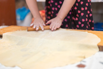 Obraz na płótnie Canvas Hands working with bread dough recipe preparation. Female hands making dough. Women's hands roll out the dough. Mom rolls dough on a kitchen board with a rolling pin