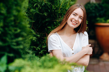Portrait of cute red-hair girl higging herself and wide smiling posing outdoor.- Image
