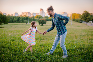 Fototapeta premium little girl kid daughter holding her father hand in the background of nature at sunset.