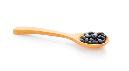 Black beans in wooden spoon isolated on white background.
