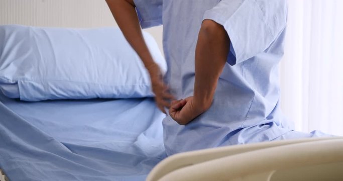 Close up of senior male patient having back ache on hospital bed