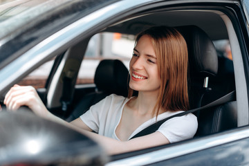 Fototapeta na wymiar Gladness young woman drive a car and happily smiling .- Image