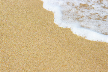 Golden sand and sea wave with foam, summer background, copy space