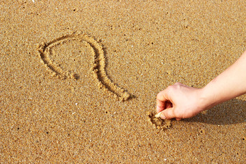 Male hand draws on sand question mark, top view