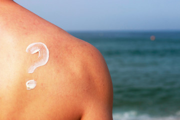 Question mark drawn by sunscreen on male back, skin protection concept