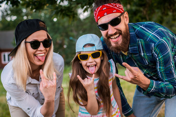 Funny man, woman and child with protruding tongues in rocker style scream.
