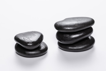 A close up view of hot massage stones isolated against a white background in a still-life setting. Small smoothed flat rocks, heated then placed on the body in a wellness spa.