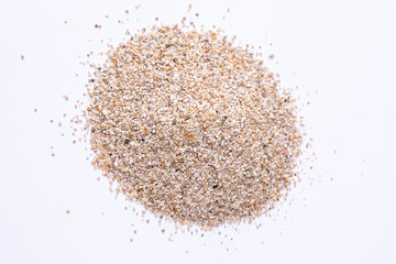 A closeup view on a small pile of sand isolated against a white background in the studio. Heaped grains of sand from the beach.