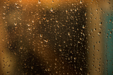 texture of rain drops on dirty window glass over blur and cloudy sunset sky background