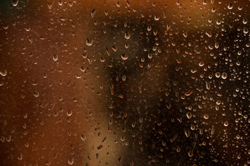 texture of rain drops on dirty window glass over blur and cloudy sunset sky background