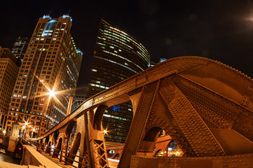 Dramatic shot of a vintage Chicago draw bridge with the skyline in the background at night