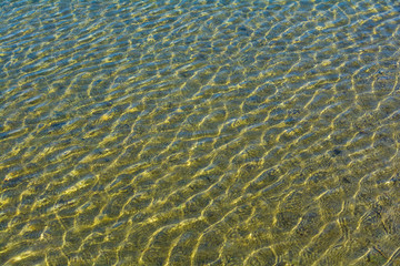 Ripples on the surface of the sea water with sun highlights.