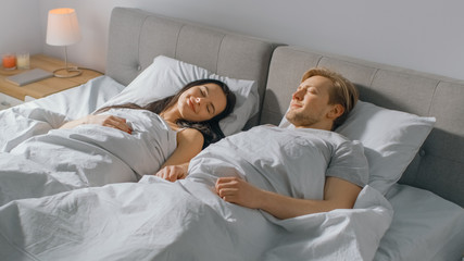 In the Morning Cute Young Couple Sleeping Cozily in Bed. Young People in Love. Early Morning Sun Shines Through the Window. 