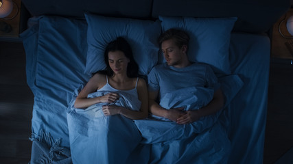 Cute Young Couple Sweetly Sleeping in the Bed. Dark Cozy Room.
