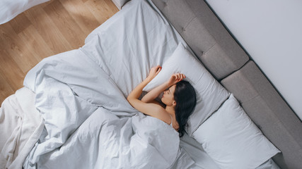 Attractive Brunette Cozily Sleeps in Her Bed while Early Morning Sunrays Illuminate Her. Warm, Cozy...