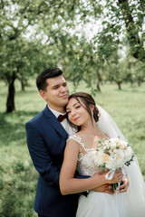 bride and groom on a wedding walk in the park; tender feelings for newlyweds