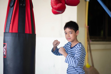 Little Asian boy learn and train boxing with punch bag