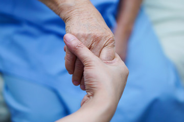 Caregiver holding hands Asian elderly woman patient with love, care, encourage and empathy at...