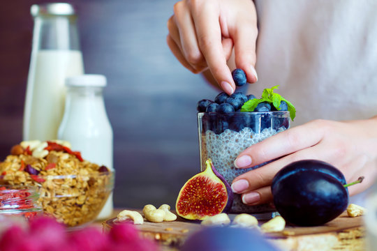 Closeup Female Hands Are Preparing Organic Yogurt With Chia For Good Digestion, Functioning Of Gastrointestinal Tract. Summer Berries, Nuts, Fruits, Dairy Products On Table. Healthy Food Concept.