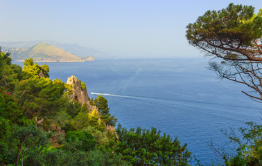 Capri Island. Magnificent view from the sea on the rocky shores of the island of Capri and the mountains surrounding the Amalfi coast in the background.