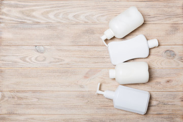 Set of White Cosmetic containers on wooden background, top view with copy space. Group of plastic bodycare bottle containers with empty space for you design