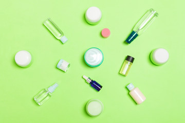 Naklejka premium Group of plastic bodycare bottle Flat lay composition with cosmetic products on green background empty space for you design. Set of White Cosmetic containers, top view with copy space