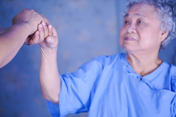 Caregiver holding hands Asian elderly woman patient with love, care, encourage and empathy at...