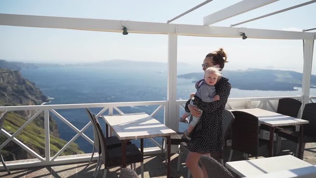 mom walks with the child in her arms in a beautiful place, a beautiful terrace with a sea view