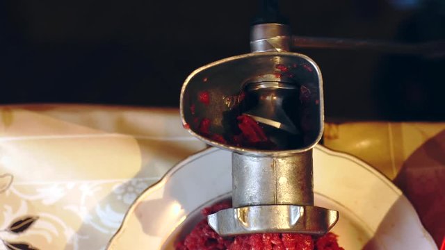 Close up shot of beef meet being minced in the manual retro mince machine.