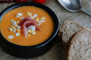 Close up of Salmorejo, creamy cold tomato soup, served with serrano ham and hard-boiled eggs. Traditional Spanish cuisine background.
