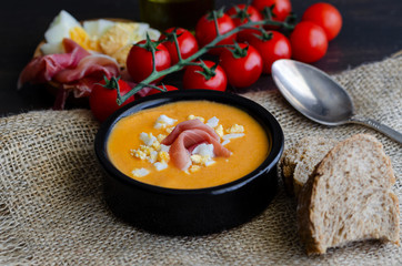 Close up of Salmorejo, creamy cold tomato soup, served with serrano ham and hard-boiled eggs. Traditional Spanish cuisine background.