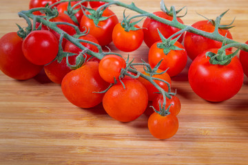 Cherry tomato clusters on the bamboo cutting board close-up