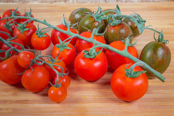 Different cherry tomato clusters on bamboo cutting board close-up