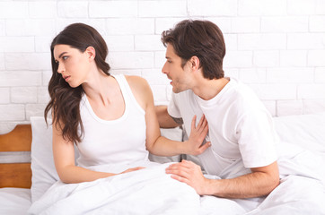 Annoyed woman refusing man in bed because of hangover
