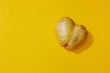 Heart shaped potato on yellow background. Minimal pop art style.