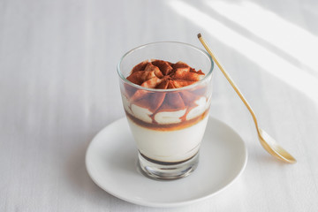 Classic tiramisu cake in a glass on white background. Layered mascarpone dessert cake. ..