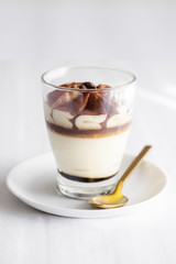 Classic tiramisu cake in a glass on white background. Layered mascarpone dessert cake. ..