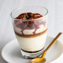 Classic tiramisu cake in a glass on white background. Layered mascarpone dessert cake. ..