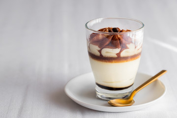 Classic tiramisu cake in a glass on white background. Layered mascarpone dessert cake. ..