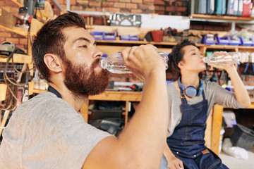 Thirsty exhausted carpenters enjoying fresh water after long day of work