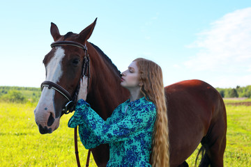 Fototapeta premium Portrait of young pretty cheerful woman with horse at summer green park